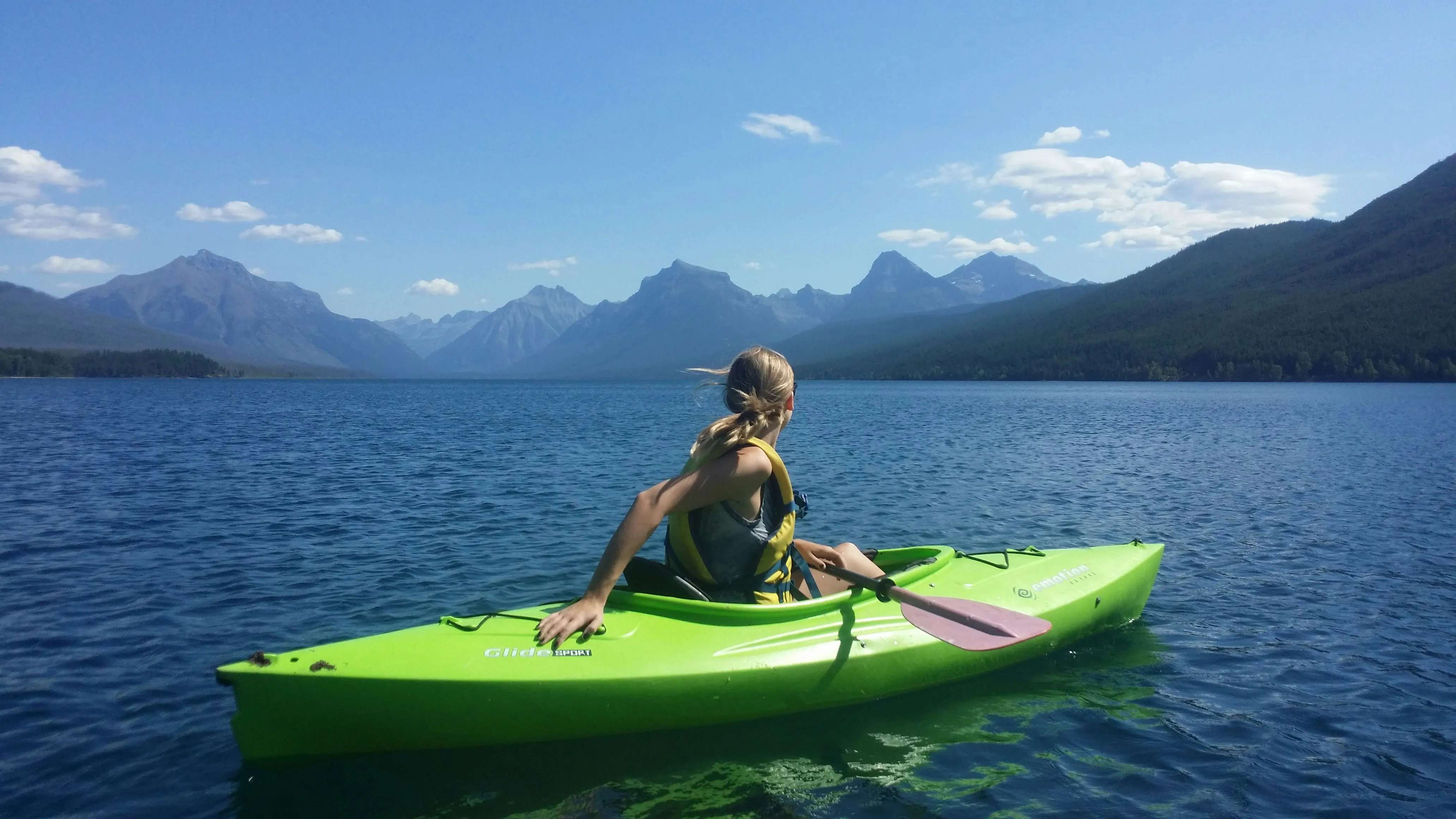 A woman on lime colored kayak in the middle of body of water