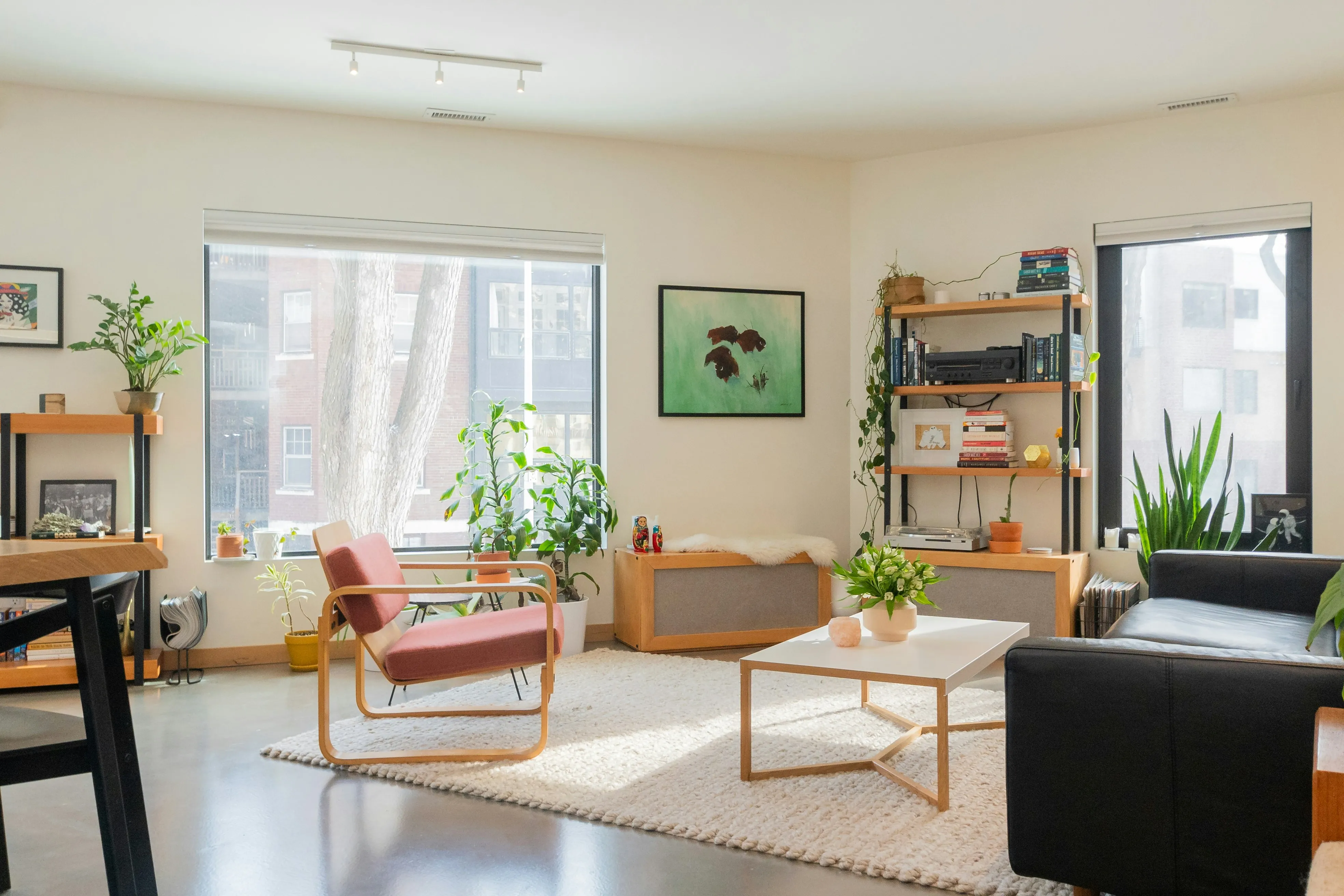 Various furnishings, including tables, chairs, sofas, cabinets, houseplants, and carpets, can be found in this elegant living room. The room has two sizable windows that look out into the nice surroundings.