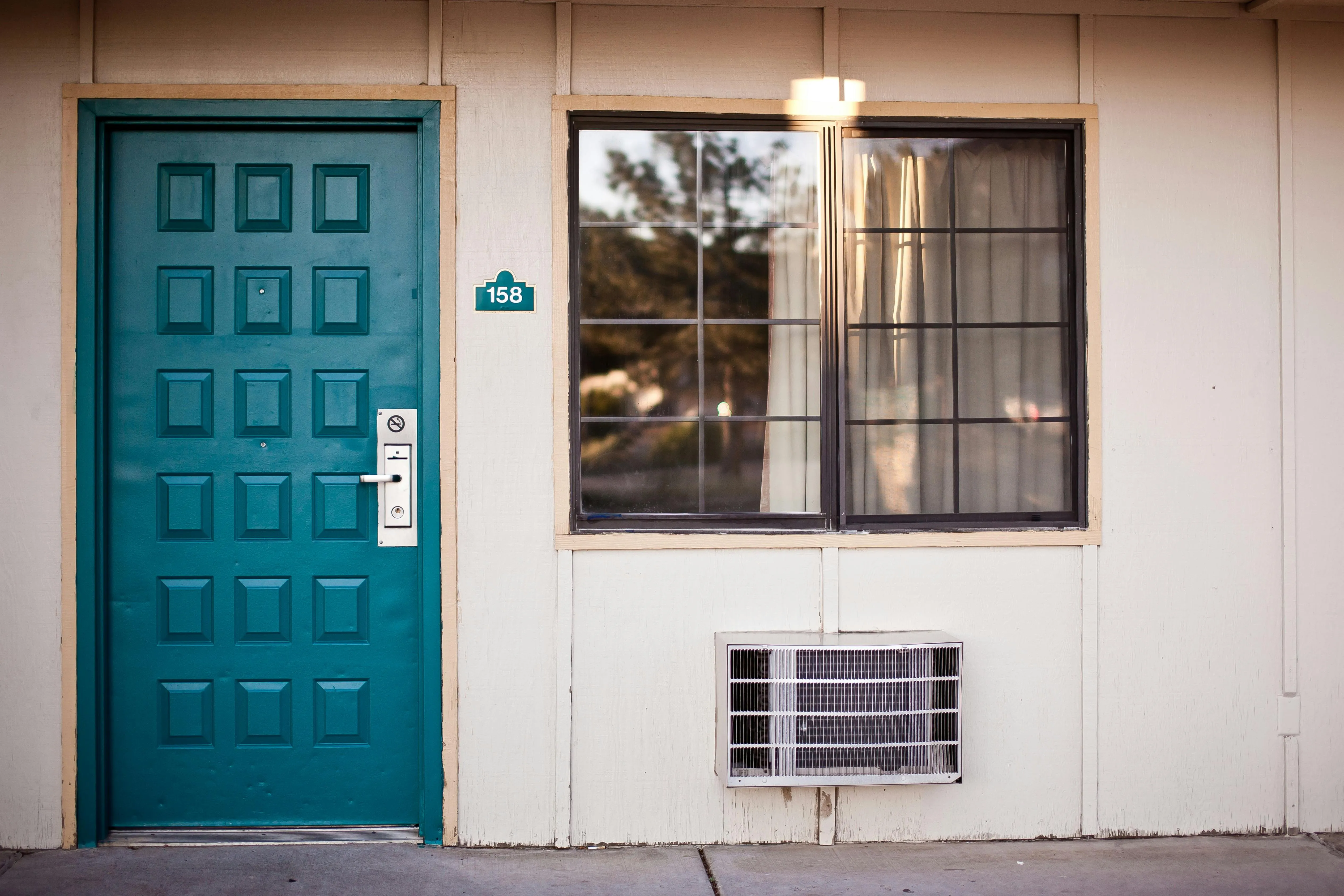 A teal wooden door beside window.