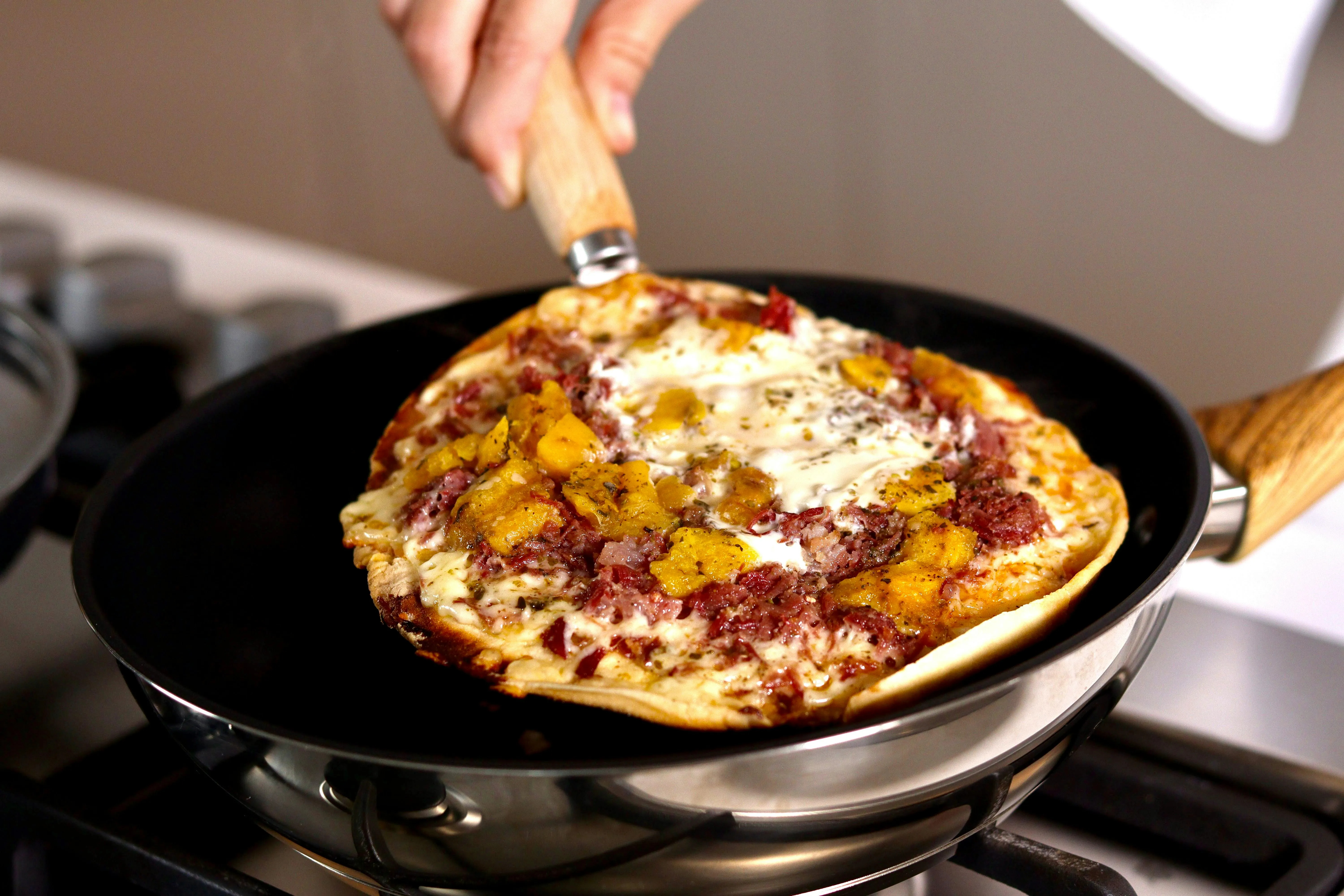 A pizza pan with a pizza in it on a stove.