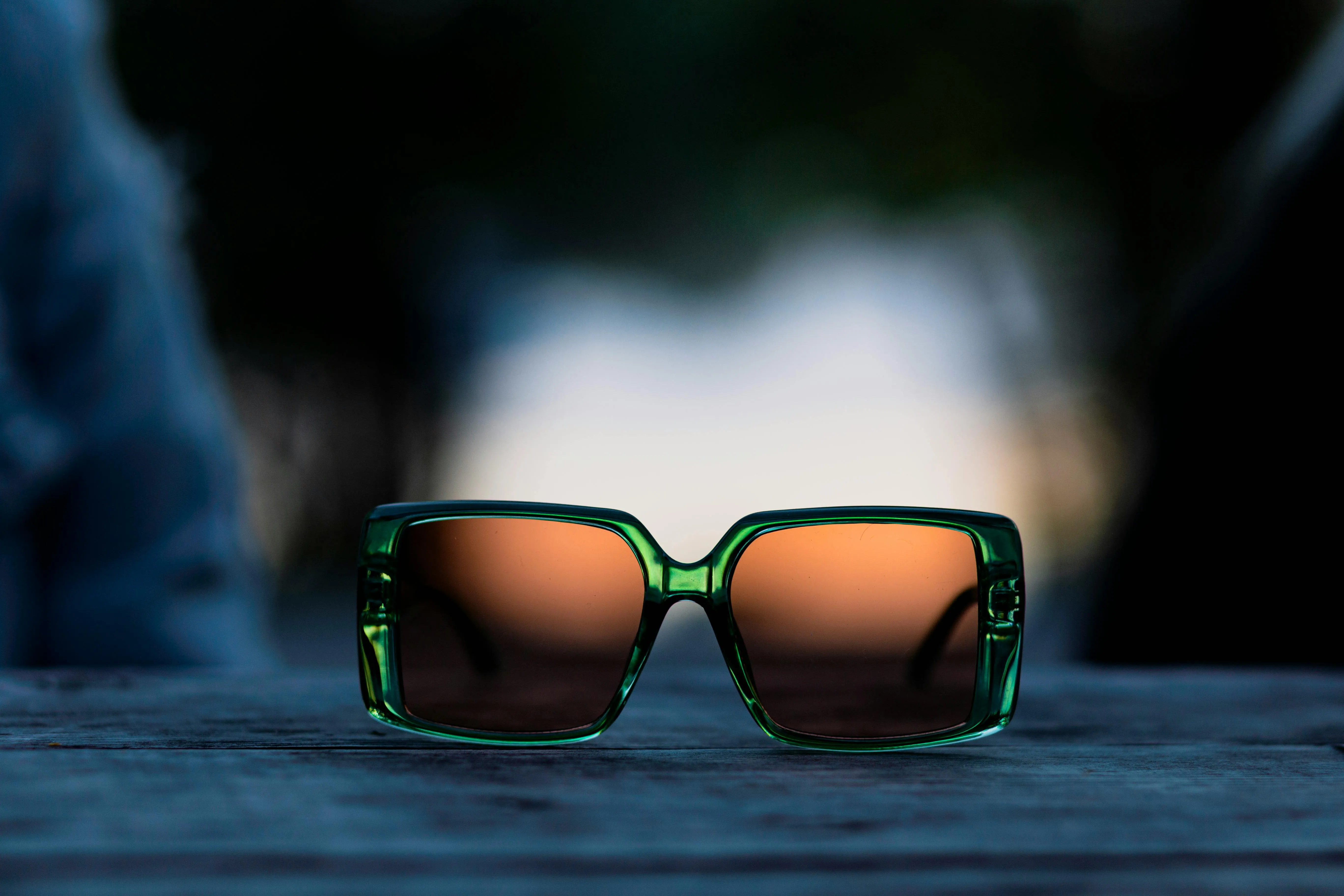 A pair of green square sunglass on wooden surface.