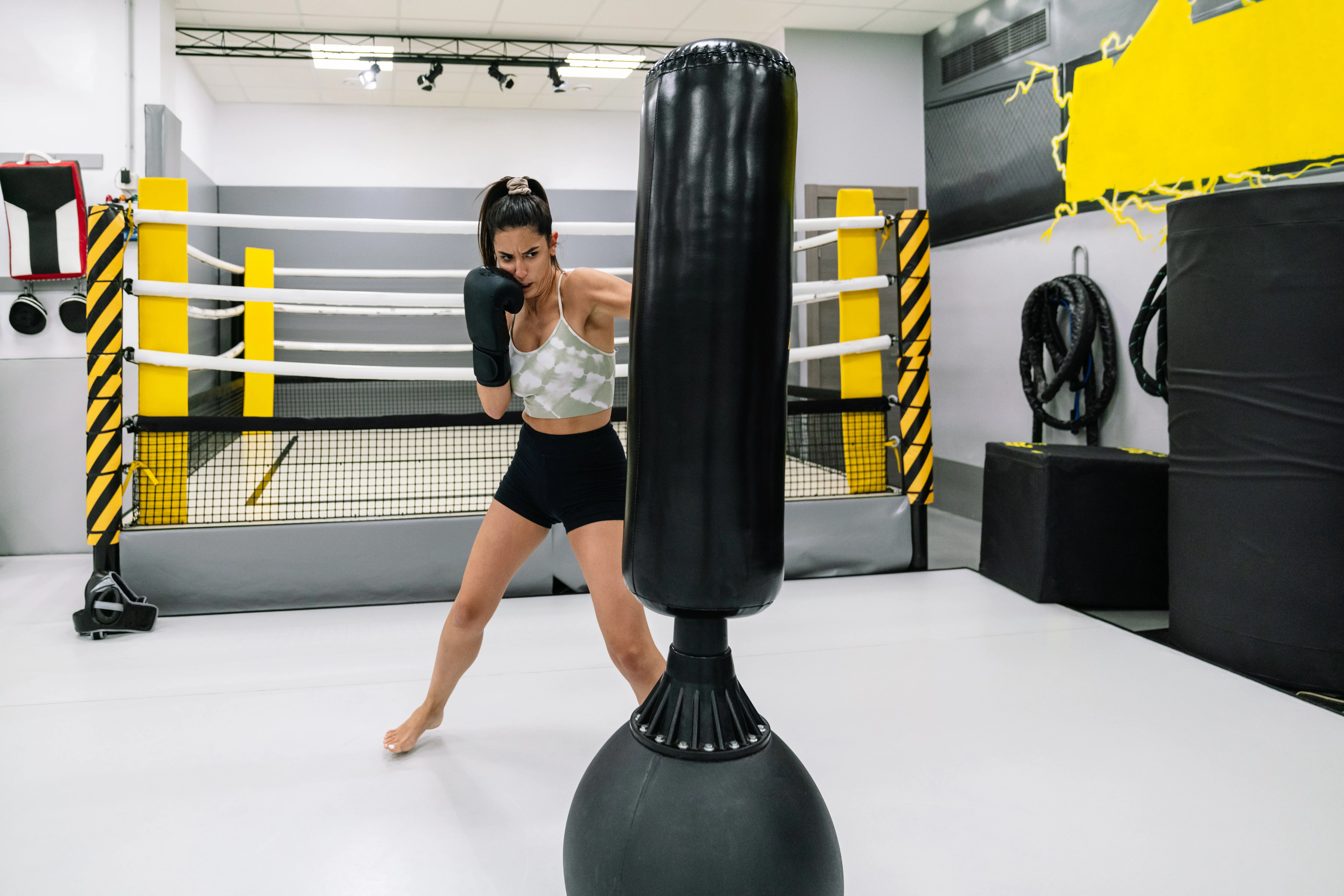 Young athlete practicing kikcboxing in gym on a free standing punching bag