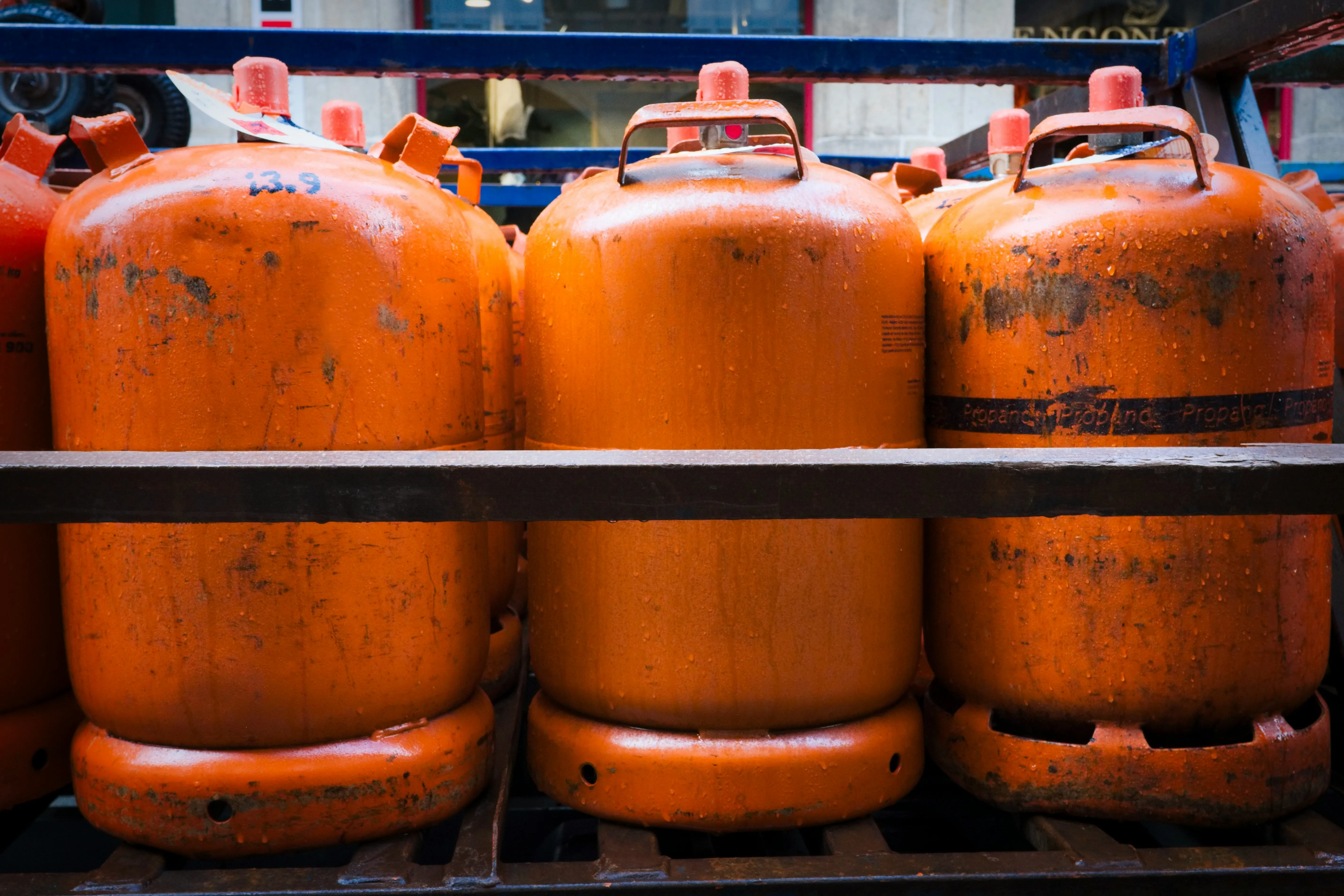 Three orange color gas cylinders on rack.