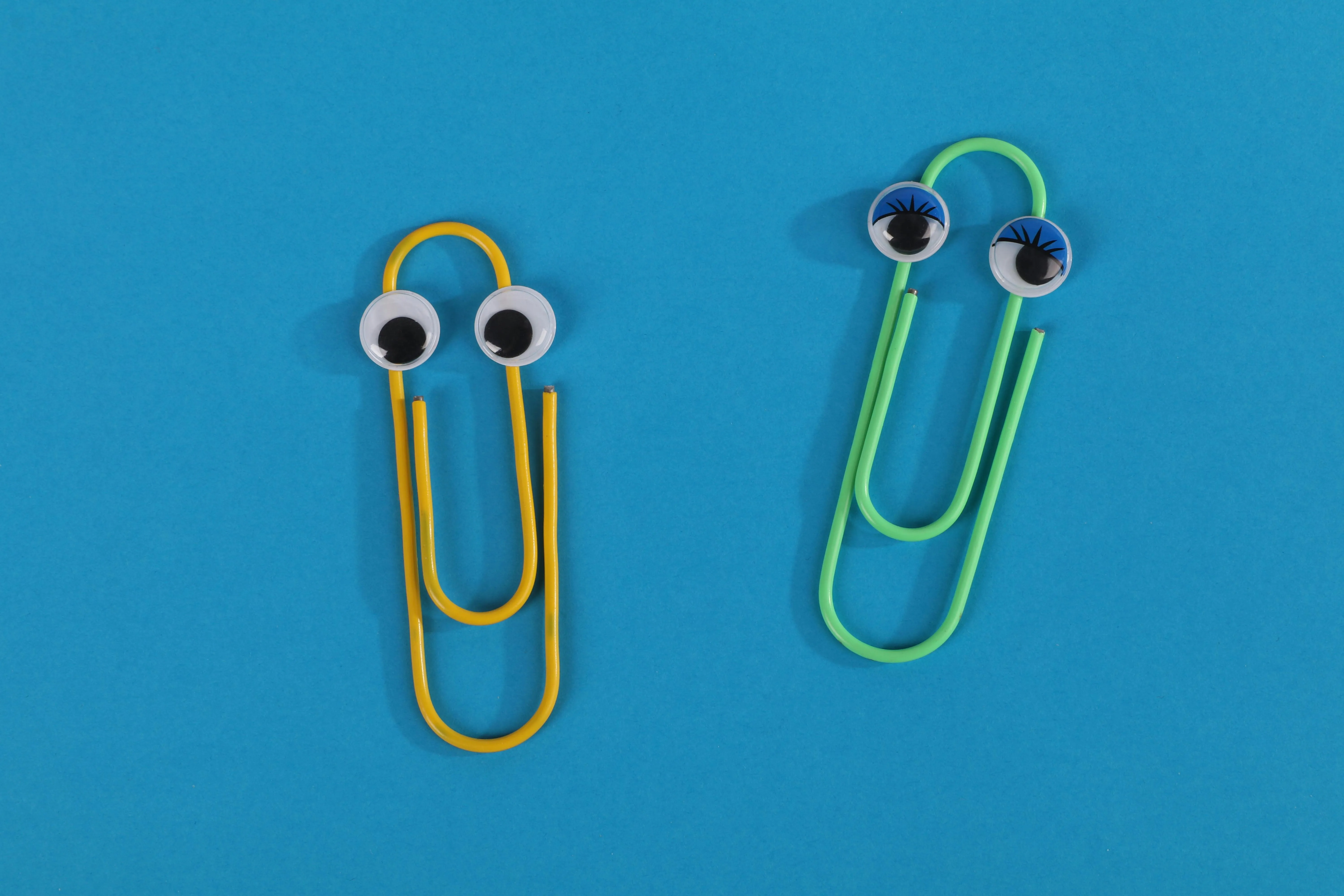 Two paper clips with googley eyes on a blue background.