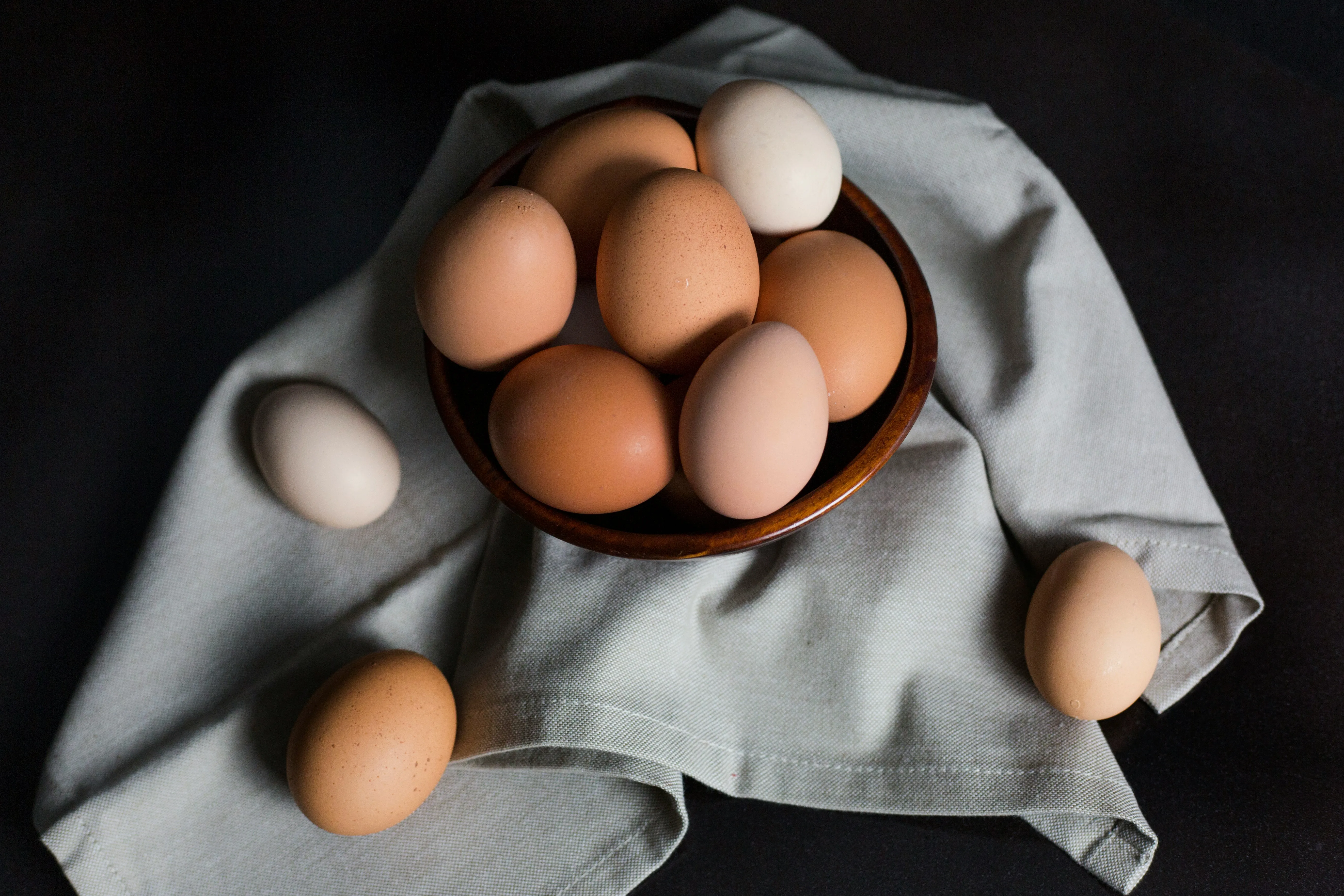 White and brown eggs in a wooden bowl placed on a regular use handkerchief