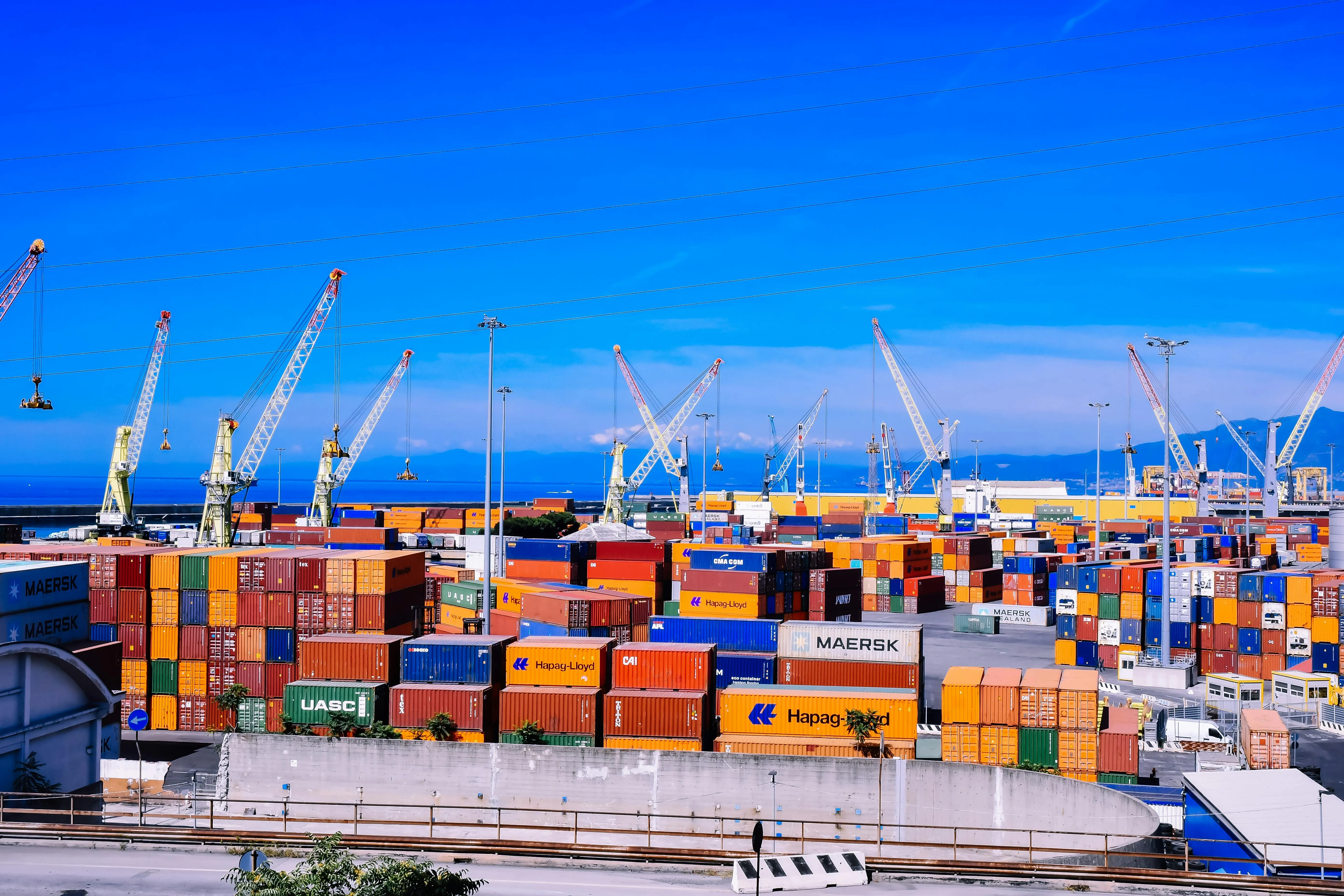 A port with cranes and shipping containers of various sizes and colors.