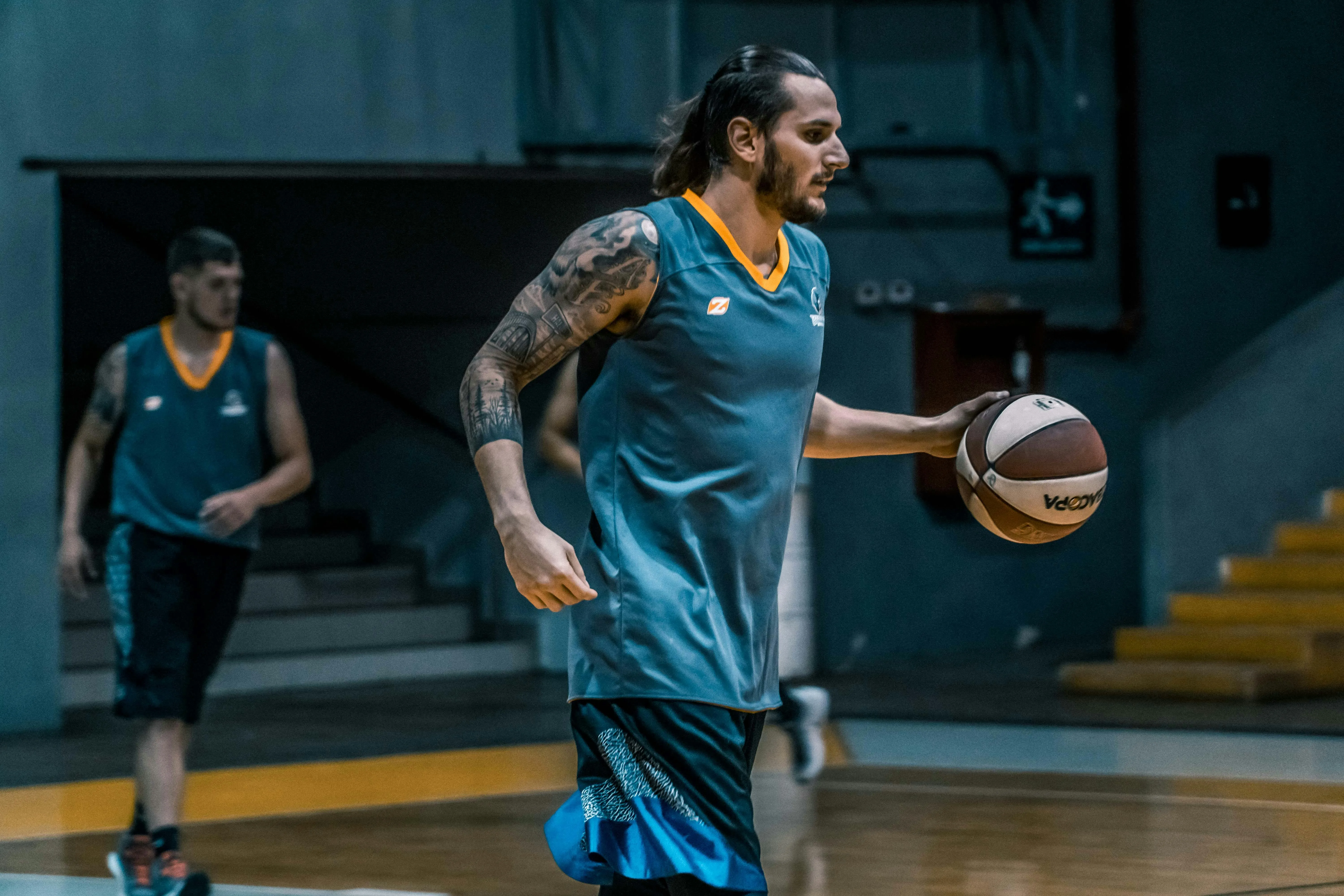 Two basketball players on a basketball field with one of them holding a basketball.