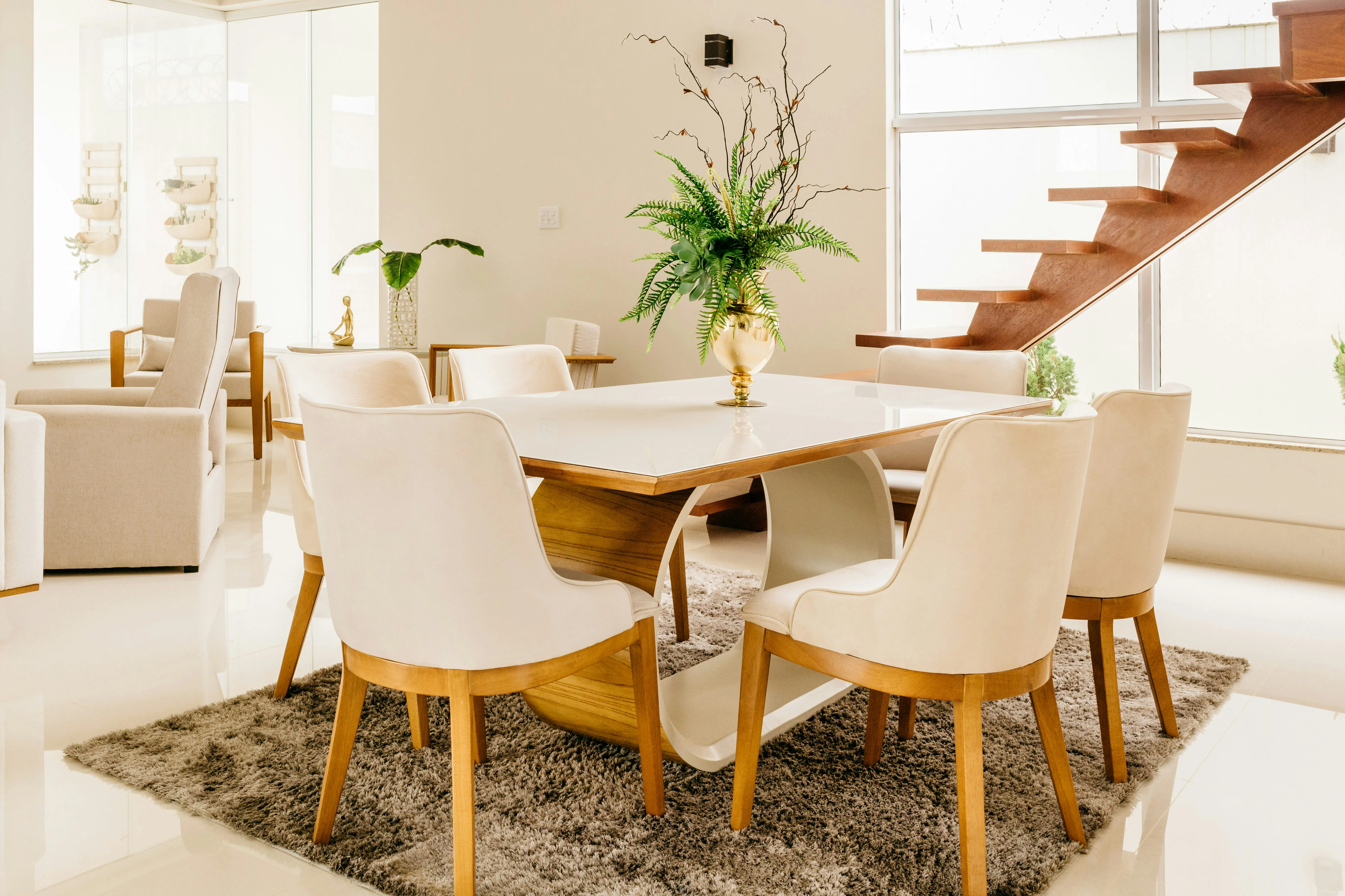 A chic dining table with four white chair. there is an ornamental plant on tob of the table.